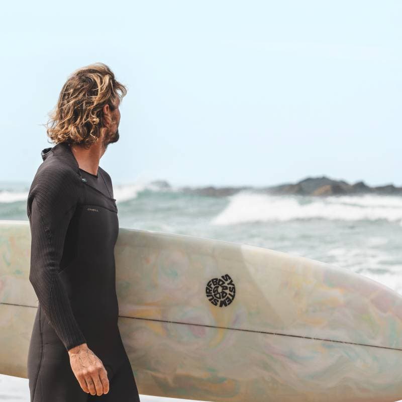 A surfer holding his surfboard in front of the ocean