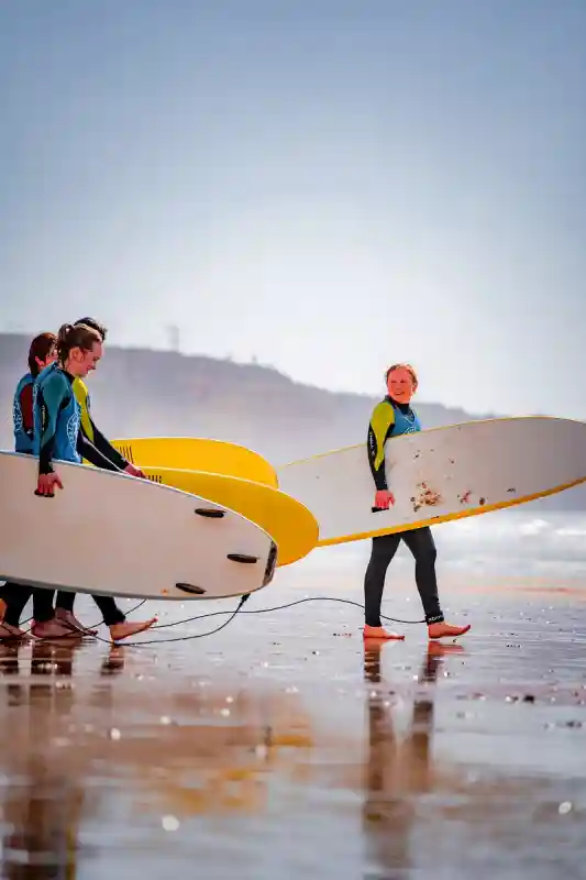 Eine Surfkurs-Gruppe läuft mit ihren Boards über den Strand bei Lagos